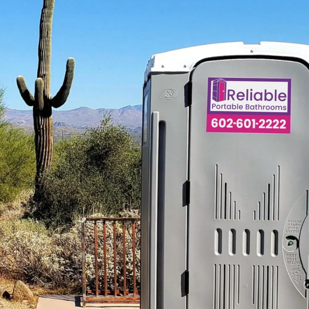 Portable bathroom units lined up outdoors on grass