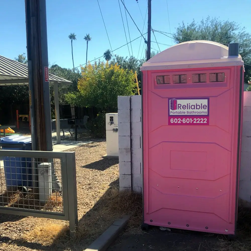 Portable restroom units lined up outdoors on gravel